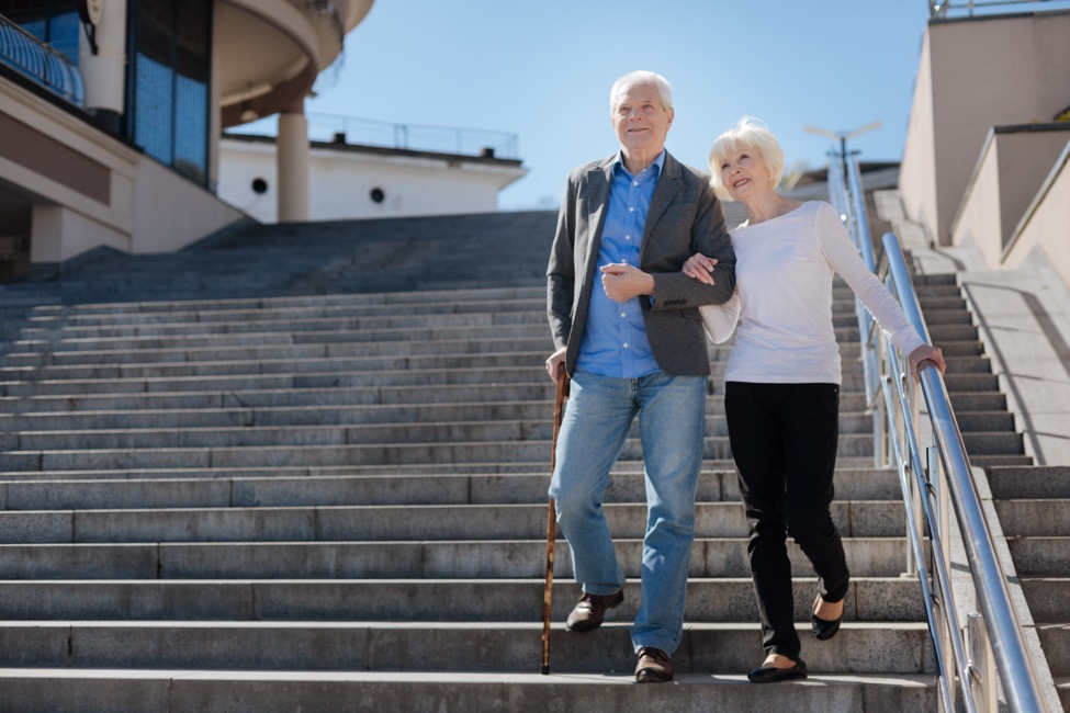 an older couple walk down concrete stairs.