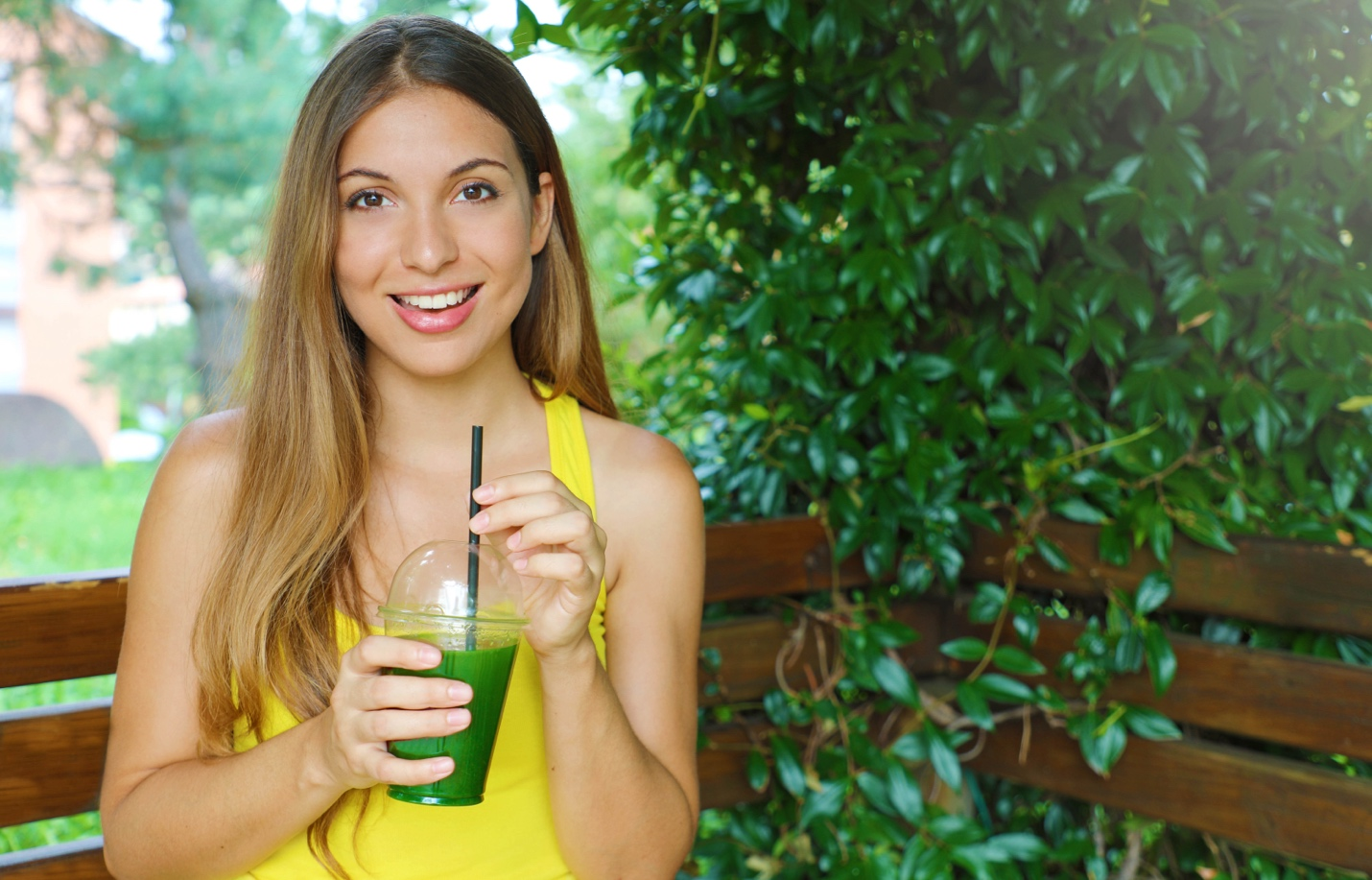 A woman sips a healthy green smoothie.